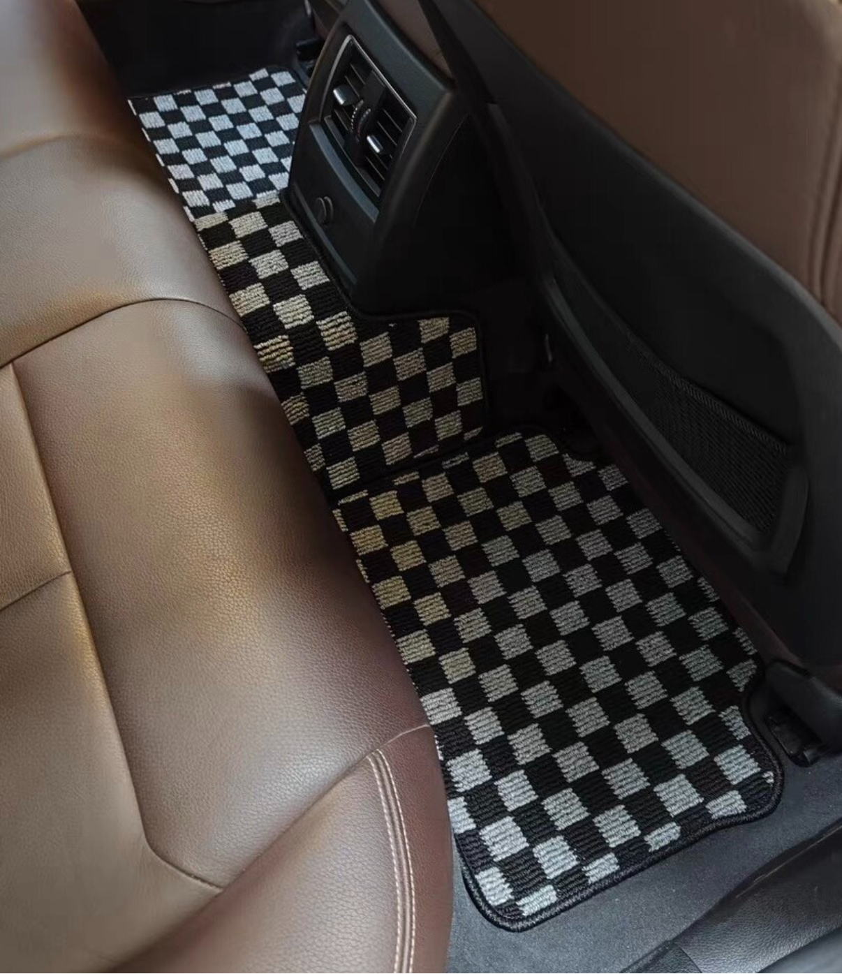 Car interior with JDM checkered floor mat on a brown leather seat