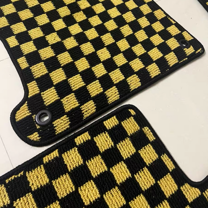 Two car mats with black and yellow checkered pattern on a white surface